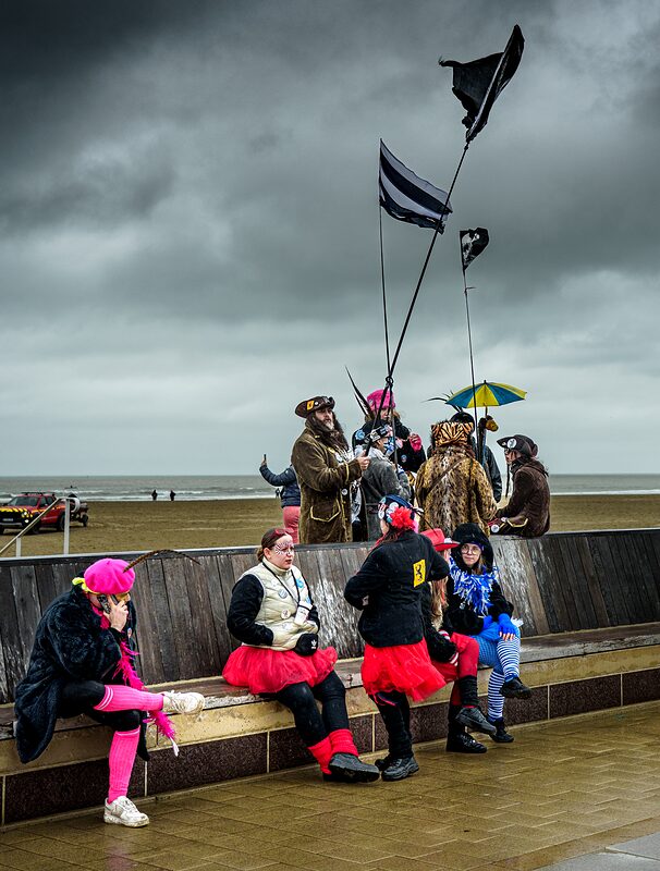 Groupe de carnavaleux grimés et colorés avec chapeaux à plumes et capes au Carnaval de Dunkerque.