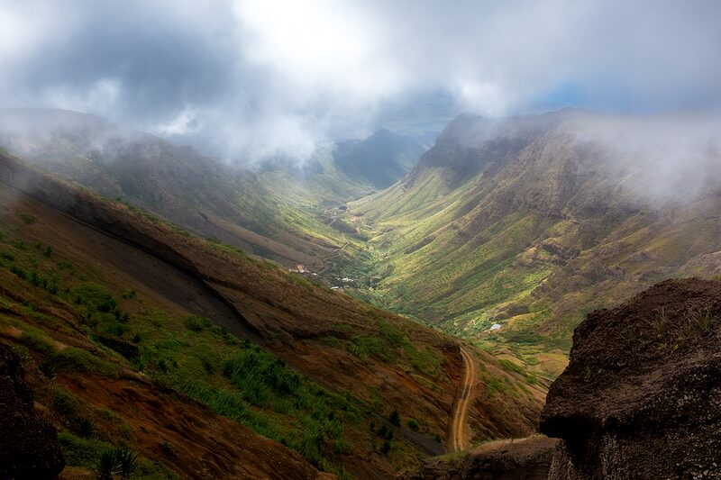 Chemin de terre serpentant dans une vallée verdoyante très encaissée du Cap-Vert, 2026.